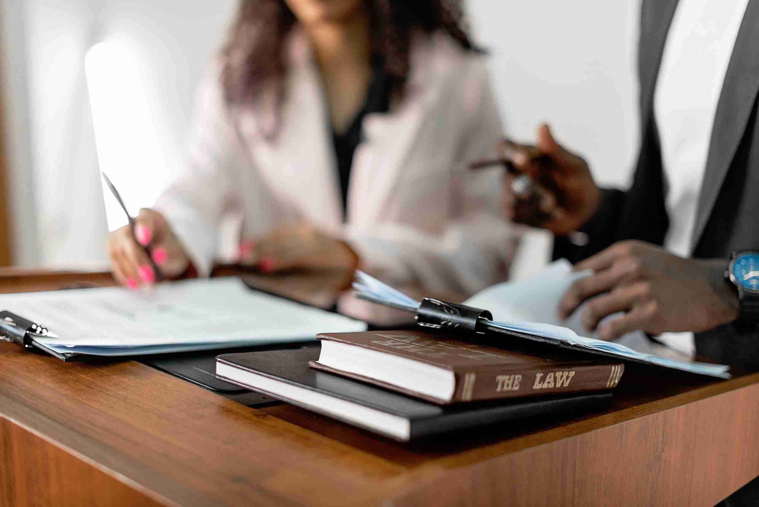 Two individuals in a lawyer's office discussing over contracts